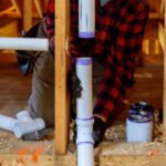 Plumber installing primer and glue PVC pipe