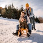 Parents enjoying sled ride with young daughter
