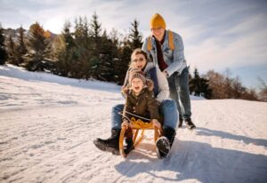 Parents enjoying sled ride with young daughter