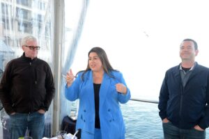 A woman delivers a speech on a boat, accompanied by two people, during an event in San Jose, CA.