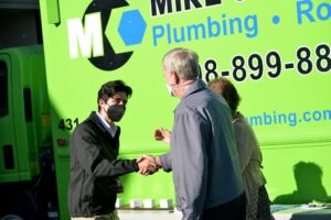 Two men shake hands, one wearing a mask, during an event in San Jose, CA.