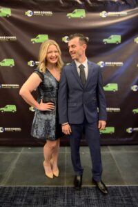 A couple standing on a green carpet at the Mike Counsil Plumbing and Rooter event in San Jose, CA