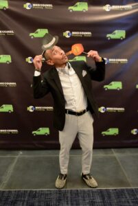 A man in a suit and tie holds a hat at the Mike Counsil Plumbing and Rooter event in San Jose, CA.