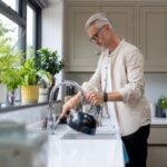 Man putting water in kettle for tea