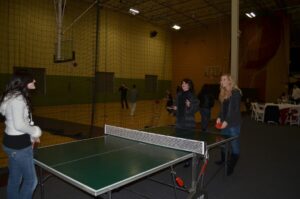 Three women playing a ping pong game at the Mike Counsil Plumbing and Rooter event in San Jose, CA.