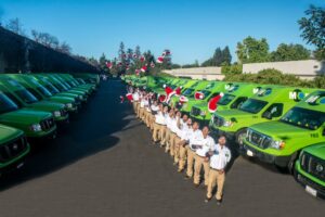 A group of people throwing Christmas caps in the air stands in front of green vans in San Jose, CA.