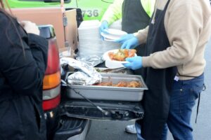 A man in an apron hands food to a woman at a Mike Counsil Plumbing event in San Jose, CA