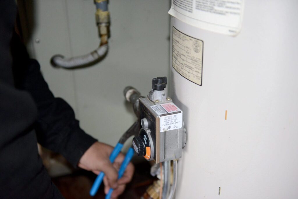 A close-up of a plumber from Mike Counsil Plumbing working on a gas water heater