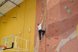 A young boy skillfully climbs a rock wall inside a gym in San Jose, CA.